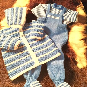 Puede incluir: Un conjunto de punto para bebé a rayas azules y blancas con una chaqueta con capucha y pantalones a juego. El conjunto está hecho de hilo suave y tiene un diseño clásico.