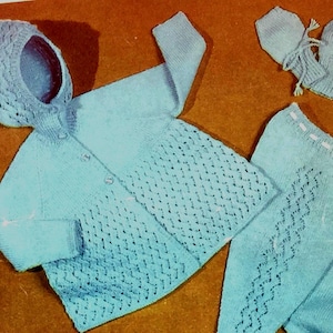 May include: A light blue knitted baby set with a hooded jacket, pants, and booties. The set features a delicate diamond pattern.