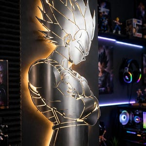 Könnte beinhalten: Eine wandmontierte Metallsilhouette der Figur Vegeta aus Dragon Ball mit gebürsteter Silberoptik und integrierter Hintergrundbeleuchtung, die einen warmen Schein um die Kanten der Figur wirft und den Charakter mit verschränkten Armen zeigt.