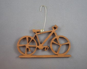 May include: A wooden bicycle ornament with a brown finish. The ornament has a wire hanger for hanging on a Christmas tree or other display.