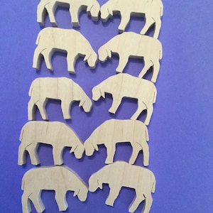 May include: Eight wooden sheep cutouts arranged in pairs on a blue background. The sheep are light-colored, with simple, stylized forms. They are facing each other, suggesting a grazing or playful interaction. Ideal for crafting or educational projects.