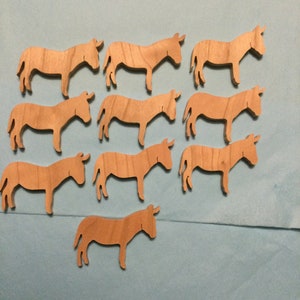 May include: A set of 10 wooden donkey cutouts, all the same size and shape. The donkeys are a light brown color and have a simple, stylized design.