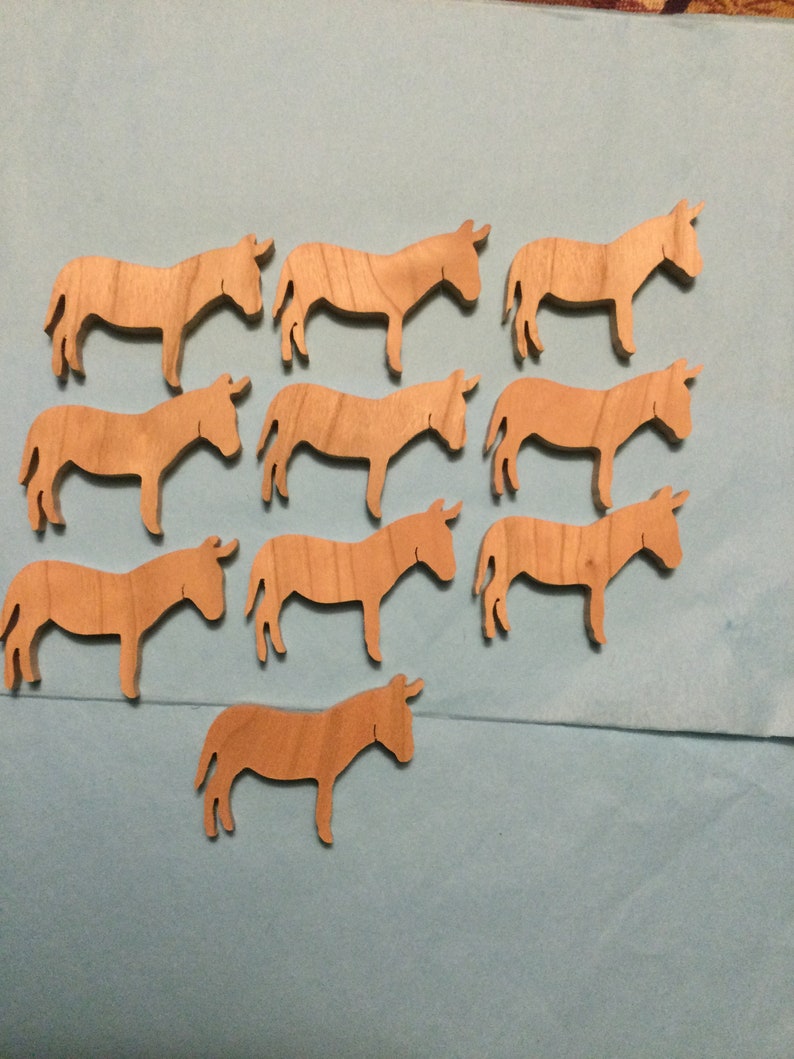 May include: A set of 10 wooden donkey cutouts, all the same size and shape. The donkeys are a light brown color and have a simple, stylized design.