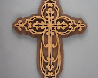 May include: A wooden cross with intricate, ornate carvings in a light brown color. The cross is set against a gray background.