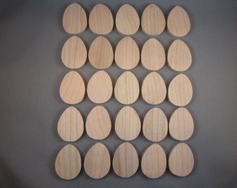 May include: Twenty-four unfinished wooden egg shapes arranged in a grid pattern. The eggs are light-colored, with visible wood grain, and are likely intended for crafting or decoration. The background is a solid gray.