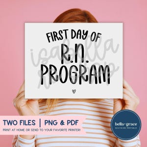 Puede incluir: Un letrero rectangular blanco con texto negro que dice FIRST DAY OF R.N. PROGRAM y un pequeño símbolo de corazón debajo. El letrero se sostiene frente a un fondo rosa sólido, presentando letras negras en negrita y un diseño sencillo.