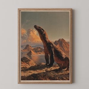 May include: A framed wall art print featuring a large Komodo dragon standing on a rocky cliffside overlooking a coastal landscape with mountains and a calm sea under a golden sunset sky with soft clouds, presented in a light wood frame.