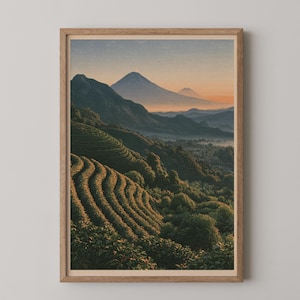 May include: A framed wall art print featuring a landscape of terraced green hills leading toward distant mountains under a soft orange and blue sunrise sky. The scene depicts rows of vegetation on rolling slopes with a hazy valley in the background.