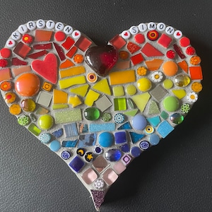 May include: A heart-shaped mosaic made of colorful glass tiles, with the names "Kirsten" and "Simon" spelled out in white letters at the top.