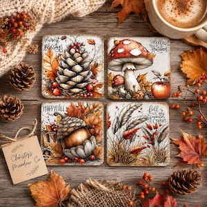 Puede incluir: Cuatro posavasos cuadrados con ilustraciones de otoño. Uno muestra una piña con el texto Harvest Blessings, uno un hongo y una manzana con Hello Autumn, uno una bellota con Happy Fall y uno tallos de trigo con Fall is my favorite color.