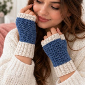 May include: Fingerless gloves featuring a textured blue crochet pattern on the main section, bordered by ribbed cream-colored cuffs at the top and bottom. The design incorporates a consistent color-blocked style with blue and cream yarn.