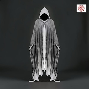May include: A hooded cloak featuring a layered design with a sheer black outer fabric that has a distressed, frayed texture over a solid white inner layer. The garment has a pointed hood and an open front, creating a high-contrast appearance.