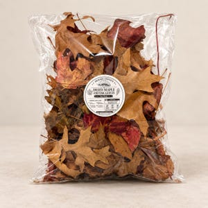 May include: A clear plastic bag filled with dried brown and red maple and oak leaves. A circular white label on the front features the text Morris Exotics, Dried Maple and Oak Leaves, 1oz Bag, and various icons and small text details.
