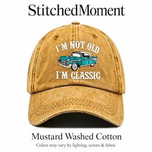 May include: A mustard yellow washed cotton baseball cap featuring an embroidered teal vintage car graphic in the centre. The white embroidered text above the car reads I'M NOT OLD and the text below the car reads I'M CLASSIC. The cap has a curved brim.