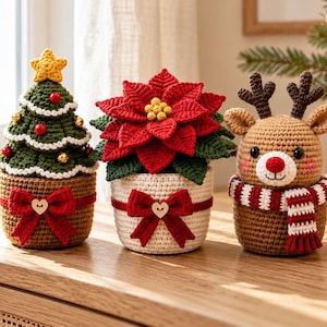 May include: Three crocheted holiday decorations: a green Christmas tree with a yellow star, a red poinsettia plant, and a brown reindeer with a red and white striped scarf. Each item is housed in a small, textured, crocheted pot.