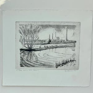 May include: A black and white etching on paper depicting a landscape with a river in the foreground, a bare tree on the bank, and an industrial factory with tall chimneys in the distance. The print includes handwritten text at the bottom.
