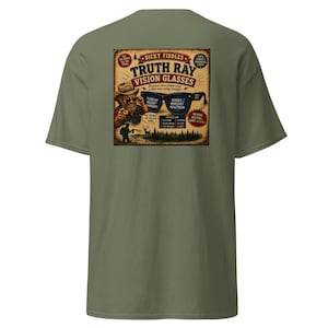 May include: An olive green t-shirt featuring a graphic on the back. The design shows a person in a hat pointing forward, a pair of sunglasses, and text that reads: Dicky Fiddles Truth Ray Vision Glasses, Filters out bullshit, reveals what they really mean.
