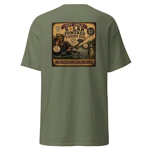 May include: An olive green t-shirt featuring a graphic on the back. The design shows a person in a boat with a solar powered fishing rod, with text reading: Dicky Fiddles Solar Powered Fishing Rod, Save the Planet, Catch a Fish, Take a Nap.