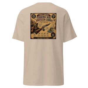 May include: A beige short-sleeve t-shirt featuring a graphic on the back. The design shows a person in a hat holding a fishing rod and shotgun combo with text that reads Dicky Fiddles Fishing Rod/Shotgun Combo and other descriptive phrases.