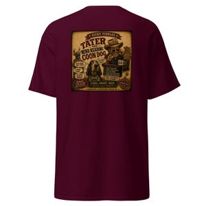 May include: A maroon short-sleeve t-shirt featuring a graphic on the back. The design depicts a man in a cowboy hat and a hound dog with text reading Dicky Fiddles Tater The Mind Reading Coon Dog, along with a list of special talents and phrases.