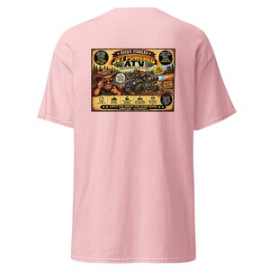 May include: A light pink t-shirt featuring a rectangular graphic on the back. The design depicts a cartoon character in a cowboy hat driving a jet-powered ATV, with text reading Dicky Fiddles Jet Powered ATV and Life's Too Short For Slow Rides.