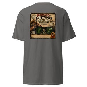 May include: A charcoal gray t-shirt featuring a graphic print on the back. The design shows a person in a hat pointing, a mug, a dog, and large sunglasses reflecting a forest scene. Text includes "Dicky Fiddles Night Vision Sunglasses".