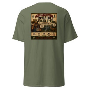 May include: An olive green t-shirt featuring a graphic on the back. The design shows a person in a hat holding a mug, a deer, and a deer stand. Text includes "Dicky Fiddles Invisible Deer Stand," "The best stand is the one they can't see!," and "If they can't see you... you can see them!" along with icons.