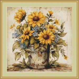 Könnte beinhalten: Ein Kreuzstichmuster mit einem Strauß aus leuchtend gelben Sonnenblumen und kleinen blauen Blumen in einem verwitterten Metalleimer. Das Motiv ist vor einem hellen, strukturierten Hintergrund platziert und von einem schlichten Goldrahmen umgeben.
