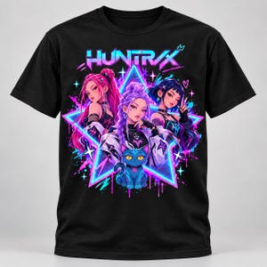 May include: A black short-sleeve t-shirt featuring a graphic print of three characters and a blue cat. The design includes a neon star background, pink and blue paint splatters, and the text "HUNTRAX" in a stylized font at the top center.