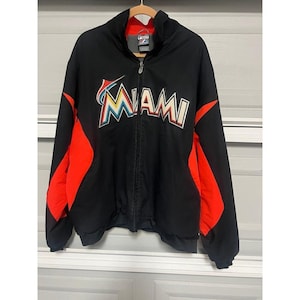 May include: A black zip-up jacket featuring the word MIAMI in white, orange, and blue lettering across the chest. The jacket includes bright orange panels along the sides and sleeves, a high collar, and a full-length front zipper closure.