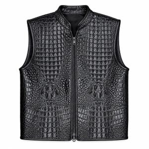 Pode incluir: Um colete preto sem mangas com uma textura em relevo de pele de crocodilo em toda a superfície. A peça inclui uma gola alta e um fecho de correr vertical central a todo o comprimento com dois puxadores de metal preto a condizer.