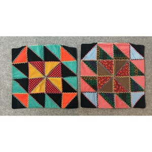 May include: Two square cushion covers featuring a patchwork star pattern. The left cover displays teal, orange, yellow, and red patterned triangles. The right cover features pink, brown, green, and blue patterned triangles with visible zigzag stitching.