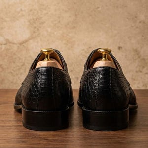 Handmade black derby shoes featuring an exotic python-pattern texture, classic lace-up design, polished finish, premium leather construction, and elegant formal silhouette for men.