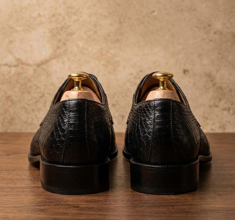 Handmade black derby shoes featuring an exotic python-pattern texture, classic lace-up design, polished finish, premium leather construction, and elegant formal silhouette for men.