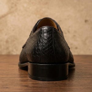 Handmade black derby shoes featuring an exotic python-pattern texture, classic lace-up design, polished finish, premium leather construction, and elegant formal silhouette for men.