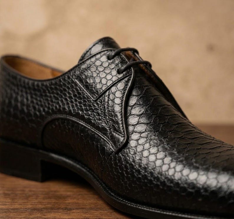 Handmade black derby shoes featuring an exotic python-pattern texture, classic lace-up design, polished finish, premium leather construction, and elegant formal silhouette for men.