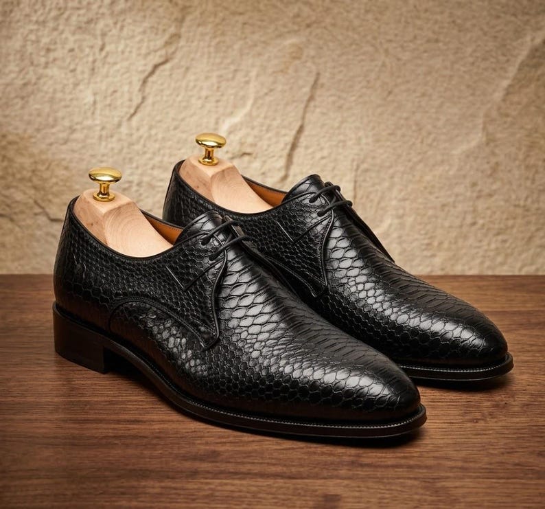 Handmade black derby shoes featuring an exotic python-pattern texture, classic lace-up design, polished finish, premium leather construction, and elegant formal silhouette for men.