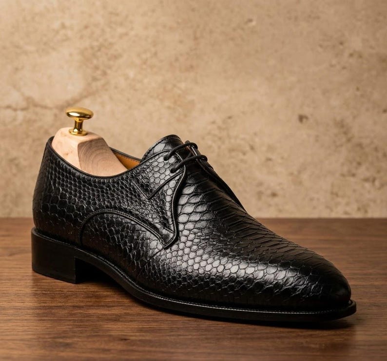 Handmade black derby shoes featuring an exotic python-pattern texture, classic lace-up design, polished finish, premium leather construction, and elegant formal silhouette for men.