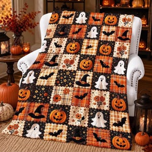 May include: A patchwork quilt featuring a repeating pattern of orange pumpkins, white ghosts, black bats, black witch hats, and orange flowers on a black and orange plaid background. The quilt is draped over a white armchair.