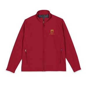 Può includere: Una giacca softshell rosso scuro con cerniera frontale integrale, colletto rialzato e due tasche laterali con zip. Sul petto sinistro è presente un logo ricamato in oro raffigurante le lettere RM sormontate da una corona e la scritta RYMEXA.
