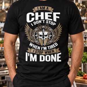 以下が含まれることがあります： I AM A CHEF I DON'T STOP WHEN I'M TIRED I STOP WHEN I'M DONEというテキストがプリントされた黒の半袖Tシャツ。中央には頭蓋骨のイラストが描かれ、その両脇に交差したナイフと翼が配置されたデザイン。