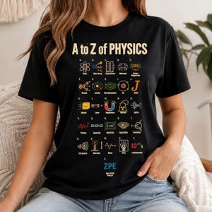 Puede incluir: Una camiseta negra de manga corta con un gráfico titulado A to Z of PHYSICS. El diseño muestra veintiséis iconos científicos coloridos y etiquetas correspondientes a las letras de la A a la Z, incluyendo términos como Atom, Gravity y ZPE.