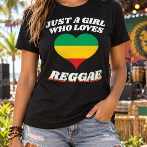 Peut inclure: Un t-shirt noir à manches courtes avec le texte blanc "JUST A GIRL WHO LOVES" au-dessus d'un cœur aux bandes horizontales verte, jaune et rouge, suivi du texte blanc "REGGAE" avec une ombre portée orange subtile.