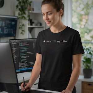 May include: A black short-sleeved t-shirt featuring a white padlock icon followed by the green text "chmod 777" and the white text "my life" printed across the chest area in a clean, sans-serif font style.
