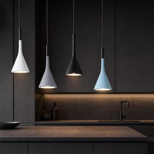 May include: Four pendant lights with conical shades in white, light gray, black, and light blue. Each lamp features a thin black cord and a black cylindrical top connector. The lights are illuminated, casting a warm glow downward from the base.