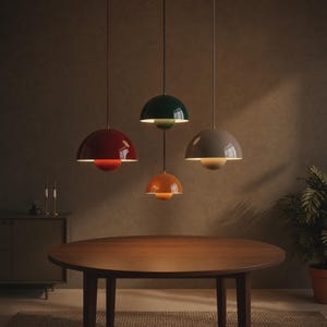 May include: Four pendant lights with a dome-shaped design suspended from the ceiling. The lights feature a layered structure with a larger upper dome and a smaller lower dome, colored in red, dark green, orange, and light gray respectively.