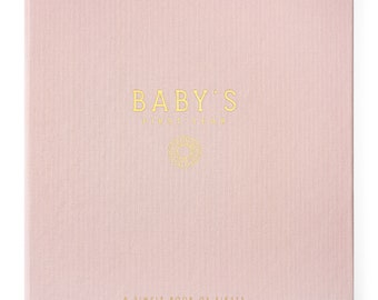Op de afbeelding: Een roze boek met een linnen omslag en gouden letters met de tekst "BABY'S FIRST YEAR" en "A SIMPLE BOOK OF FIRSTS".
