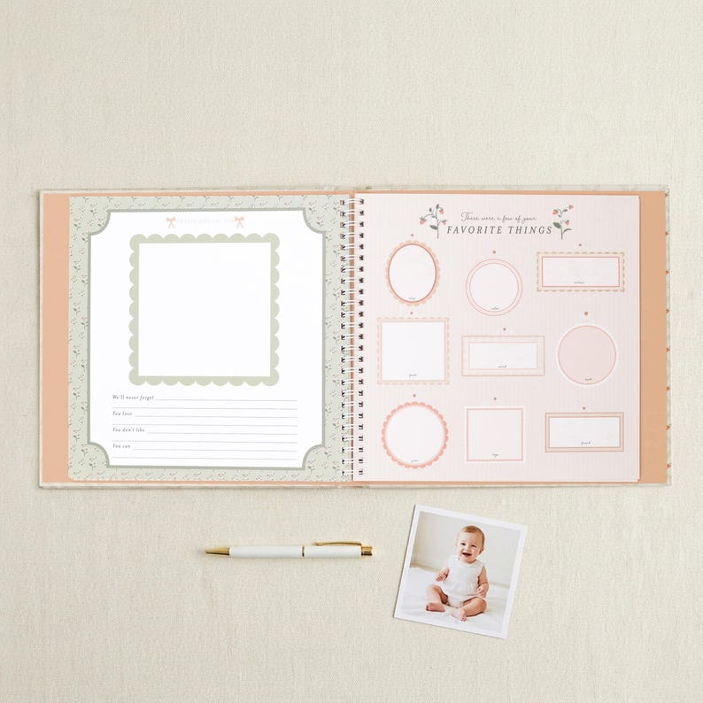 May include: An open spiral-bound memory book with a light peach cover. The left page features a scalloped photo frame and lines for notes. The right page is titled "These are a few of your FAVORITE THINGS" with various frames. A white pen and a baby photo are below.