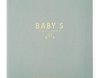 May include: A square, sage green fabric-covered memory book with gold foil lettering that reads BABY'S FIRST YEAR, accompanied by three small star icons. At the bottom, the text reads A SIMPLE BOOK OF FIRSTS in smaller gold foil letters.