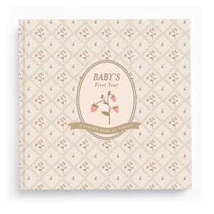 Cottage Garden baby memory book — floral garden first-year journal with a hand-illustrated bloom medallion on a beige ditsy-floral cover.